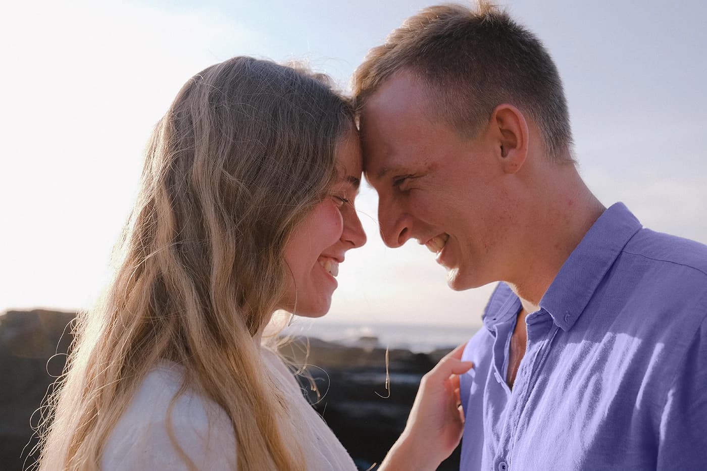 a happy couple smiling face to face outdoors in the sun